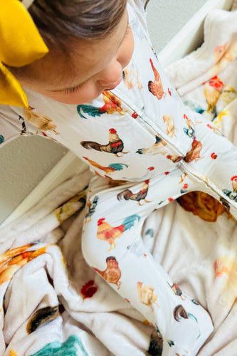 Person wearing a patterned outfit with rooster design, sitting on a bed.