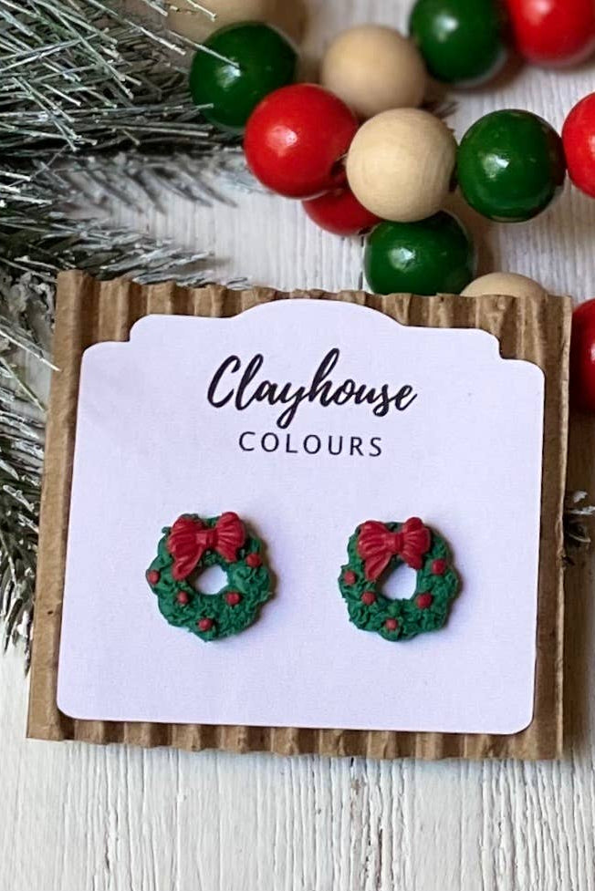 Christmas-themed earrings on a 'Clayhouse Colours' card with decorative beads and branches in the background.