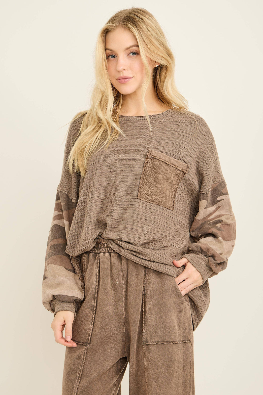 Woman wearing a brown ribbed sweater and pants on a plain background