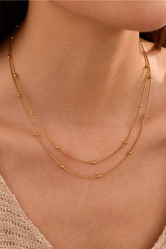 Gold necklace on a person wearing a beige cardigan