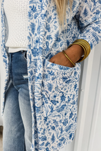 Load image into Gallery viewer, Person wearing a blue floral cardigan over a white sweater and jeans, with a neutral background.