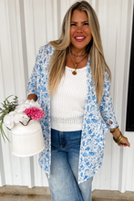 Load image into Gallery viewer, Woman wearing a blue floral cardigan, white sweater, and jeans, holding flowers.