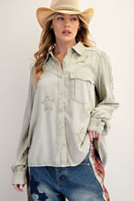 Load image into Gallery viewer, Woman wearing a light-colored denim shirt with star patterns and blue jeans, standing against a plain background.
