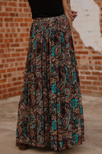 Load image into Gallery viewer, Long patterned skirt worn by a person against a brick wall.
