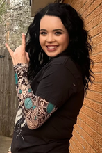Load image into Gallery viewer, Woman with tattoos on arm making a peace sign against a brick wall.