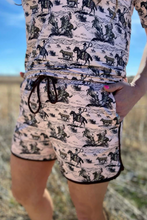 Load image into Gallery viewer, Person wearing a romper with cowboy print in an outdoor setting